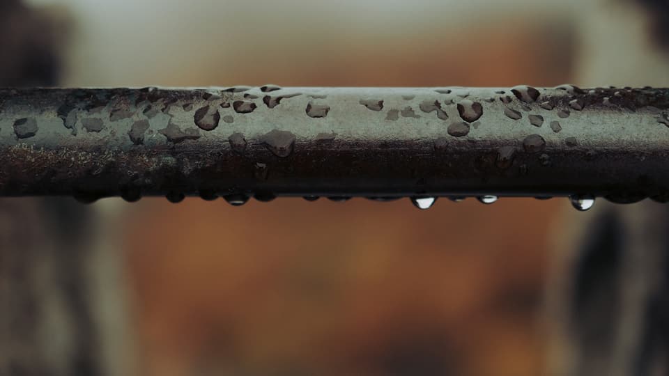Water droplets beading on a rusted metal pipe